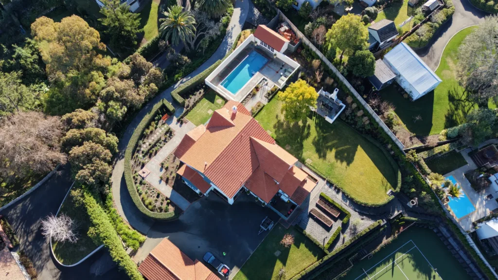 Aerial view of a large home with an orange tiled roof, swimming pool and landscaped gardens