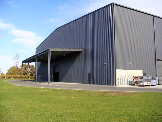 Dark grey steel-clad winery building with a covered entrance canopy
