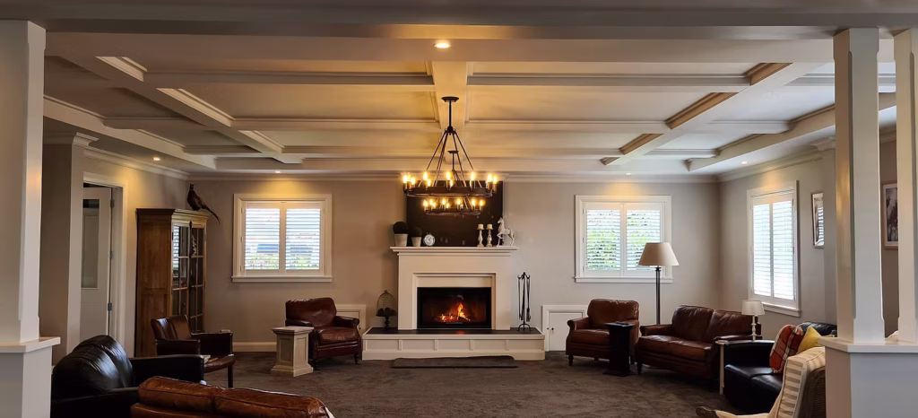 Lounge with a coffered ceiling, chandelier, fireplace and leather sofas