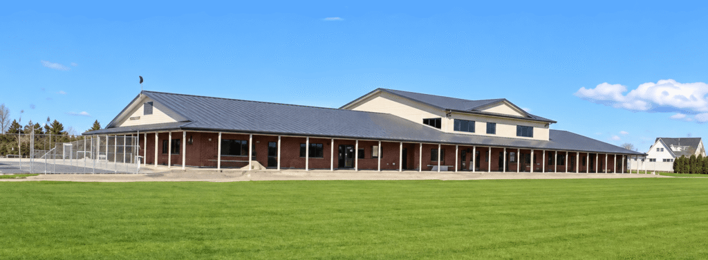 Long school building with a covered verandah beside a grass sports field